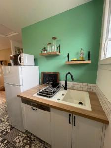 a kitchen with a sink and a white refrigerator at La maison d'Aurore et Patrice - jacuzzi couvert et jardin privés in Élincourt-Sainte-Marguerite +31 photos