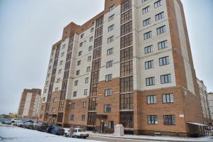 un grande edificio in mattoni con macchine parcheggiate di fronte di ЖК Бавария в центре города ad Aqtöbe