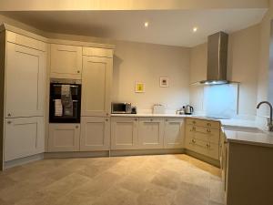 a large kitchen with white cabinets and a sink at The Stables - North Ferriby in North Ferriby