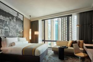 a hotel room with a bed and a couch and a window at Hotel Stripes Kuala Lumpur, Autograph Collection in Kuala Lumpur