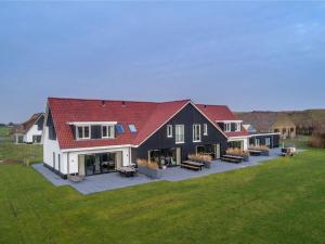 a large house with a red roof on a green field at Villa on Texel near Krimbos Forest in De Cocksdorp