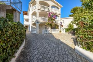 a house with a balcony on a cobblestone street at Apartments Perisa in Rogoznica