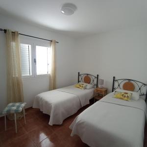 two beds in a white room with a window at GAVIOTA RELAX in Tarajalejo