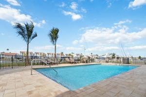 een zwembad met palmbomen naast een hek bij Luxury Waterfront Condo, Bay Views in St Pete Beach
