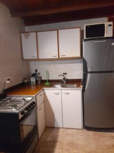 a kitchen with a stainless steel refrigerator and white cabinets at Departamento 3 ambientes, para 4 personas, barrio tranquilo a una cuadra del bosque in Pinamar +6 photos