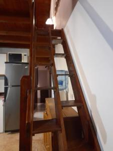 a wooden staircase leading up to a kitchen with a refrigerator at Departamento 3 ambientes, para 4 personas, barrio tranquilo a una cuadra del bosque in Pinamar