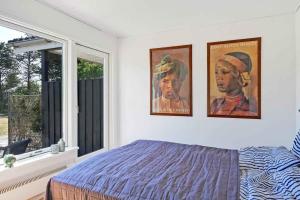 a bedroom with two pictures hanging on the wall at Lovely Cottage Full Of Holiday Atmosphere in Rødby