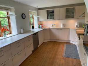 a kitchen with white cabinets and a wooden floor at Idyllic Country House On Bornholm in Neksø