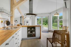 a kitchen with white cabinets and a table and chairs at Scenic Summer House Near Quiet Lapping Waves in Kirke-Hyllinge