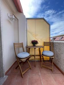 two chairs and a table on a balcony at Piso en calle peatonal. in Boiro