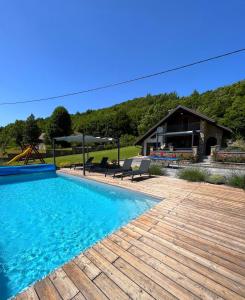 a swimming pool with a wooden deck and a house at Liko Diko Holiday Home in Gospić