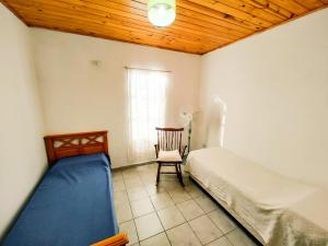 a bedroom with a bed and a chair and a window at Alojamiento Villa Elisa in Villa Elisa