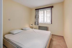 ein Schlafzimmer mit einem weißen Bett mit einem Fenster in der Unterkunft Seila 0103 P in Saint-Idesbald