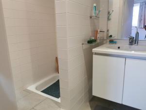 a white bathroom with a sink and a bath tub at Vlierhof in Sint-Idesbald