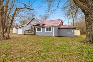 a white house with a red roof in a yard at Creekside Cabin - Beaver Lake Creek Access in Rogers