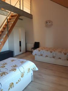 a bedroom with two beds and a staircase at Gîte les Griffons in Clairvaux-les-Lacs