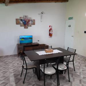 una sala da pranzo con tavolo, sedie e televisione di Un Rincón De Lourdes a San Rafael