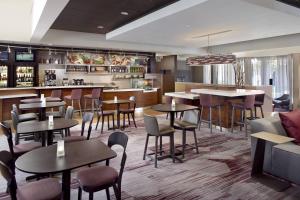 a restaurant with tables and chairs and a bar at Courtyard Charlotte Arrowood in Charlotte