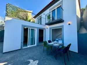un patio con tavolo e sedie di fronte a una casa di Casa Do Tempo com Jacuzzi a Ribeira Brava