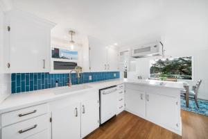 a white kitchen with white cabinets and blue tiles at Seaside Castle in Seaside +29 photos
