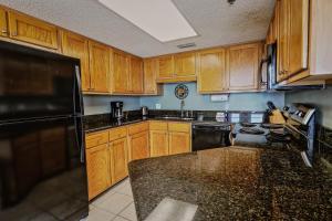 a kitchen with wooden cabinets and a black refrigerator at Phoenix V 902 in Orange Beach