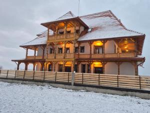 a large wooden house with a snow covered roof at Zestrea Maramureșului Săpânța in Săpînţa