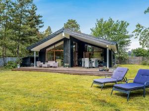 una casa con dos sillas azules en el césped en 5 star holiday home in Væggerløse, en Bøtø By