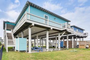 ein blaues Haus mit weißen Säulen und einem Balkon in der Unterkunft The Beach House Bolivar Peninsula Family Getaway in Crystal Beach