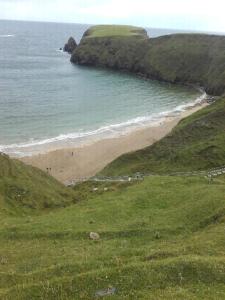 a beach with people walking on the sand and the ocean at Ard A Mhaoire in Glendorragha