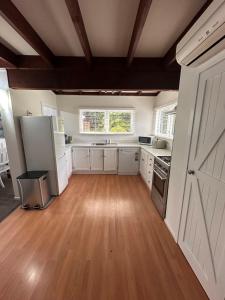 a large kitchen with white cabinets and a wooden floor at Lake Okareka Calder Road Cottage in Rotorua