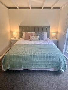 a bedroom with a large bed with two lamps at Lake Okareka Calder Road Cottage in Rotorua +9 photos