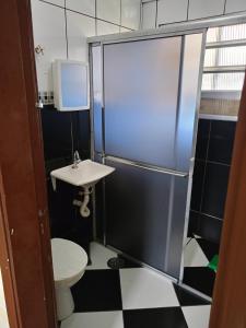 a bathroom with a shower with a sink and a toilet at Praiamongagua in Mongaguá