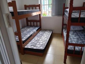 three bunk beds in a room with a window at Praiamongagua in Mongaguá