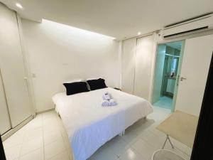 a bedroom with a white bed with a teddy bear on it at Flat em frente ao mar com piscina varanda e AC in Santos