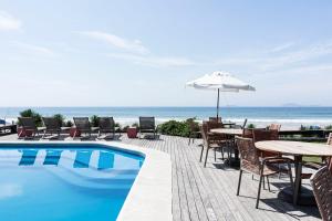 a swimming pool with tables and chairs and an umbrella at Maravista Hotel & Spa Ltda in Búzios