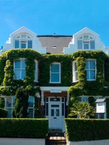 Uma casa branca com hera verde. em Marple Cottage Guest House em Londres