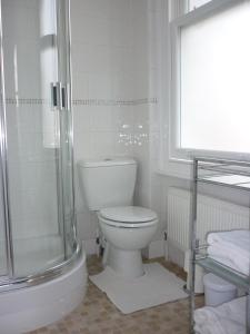 a white bathroom with a toilet and a shower at Marple Cottage Guest House in London