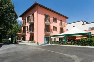 a pink building with a parking lot in front of it at Hotel Mosca in Monza