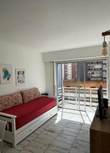 un salon avec un canapé rouge et un balcon dans l'établissement Departamento en Mar del Plata, Zona La Perla, à Mar del Plata