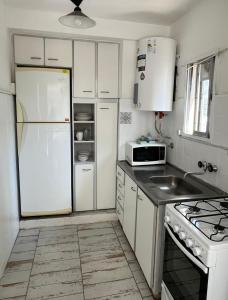 La cuisine blanche est équipée d'un réfrigérateur et d'un évier. dans l'établissement Departamento en Mar del Plata, Zona La Perla, à Mar del Plata