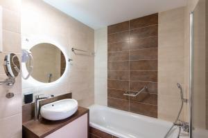 un bagno con vasca, lavandino e specchio di Sunset Resort 003 Jacuzzi a Fonyód