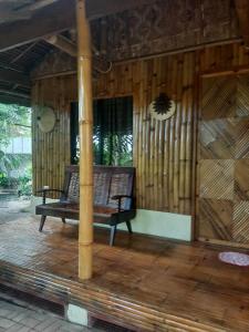 a bench on the porch of a wooden house at Dumaguete Oasis Hut near Airport and City Mall in Daro