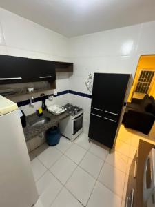 Una pequeña cocina con fregadero y estufa. en Prive 3 quartos proximo a praia, en Paulista