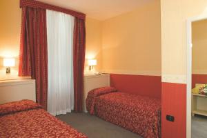 a hotel room with two beds and a window at Hotel Mosca in Monza
