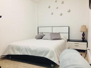 a bedroom with a bed with white sheets and butterflies on the wall at Department, Studio Type Excellent Location in Mexico City