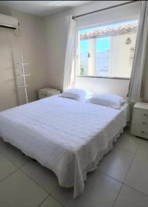 a bedroom with a large white bed with a window at casa amar guaibim in Guaibim