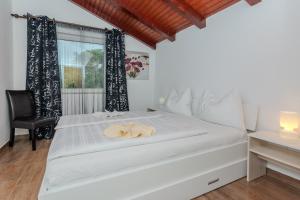 ein Schlafzimmer mit einem weißen Bett mit einem Stuhl und einem Fenster in der Unterkunft Family friendly house with a parking space Zaton, Zadar - 23570 in Zaton