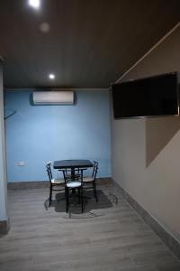 a table and chairs in a room with a tv at Hotel 1140 in Linares
