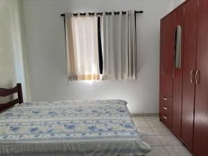 ein Schlafzimmer mit einem Bett, einer Kommode und einem Fenster in der Unterkunft Apto Próx. ao Mar na Guilhermina - Melhor Local in Praia Grande + 19 Fotos