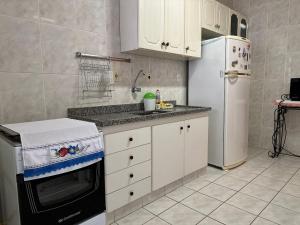 eine Küche mit Kühlschrank und Herd oberen Backofen in der Unterkunft Apto Próx. ao Mar na Guilhermina - Melhor Local in Praia Grande